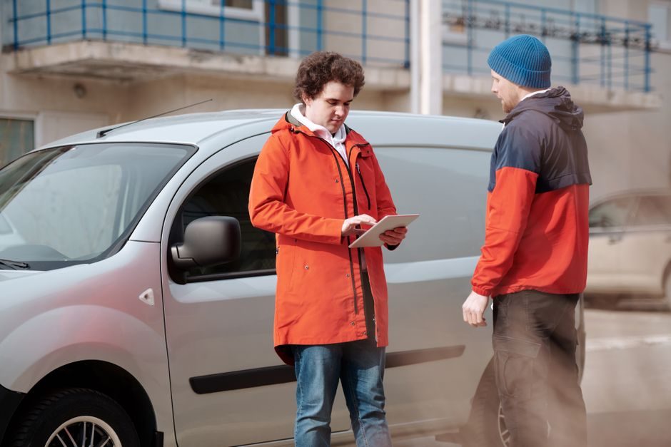 A tradesman using a tablet beside a van