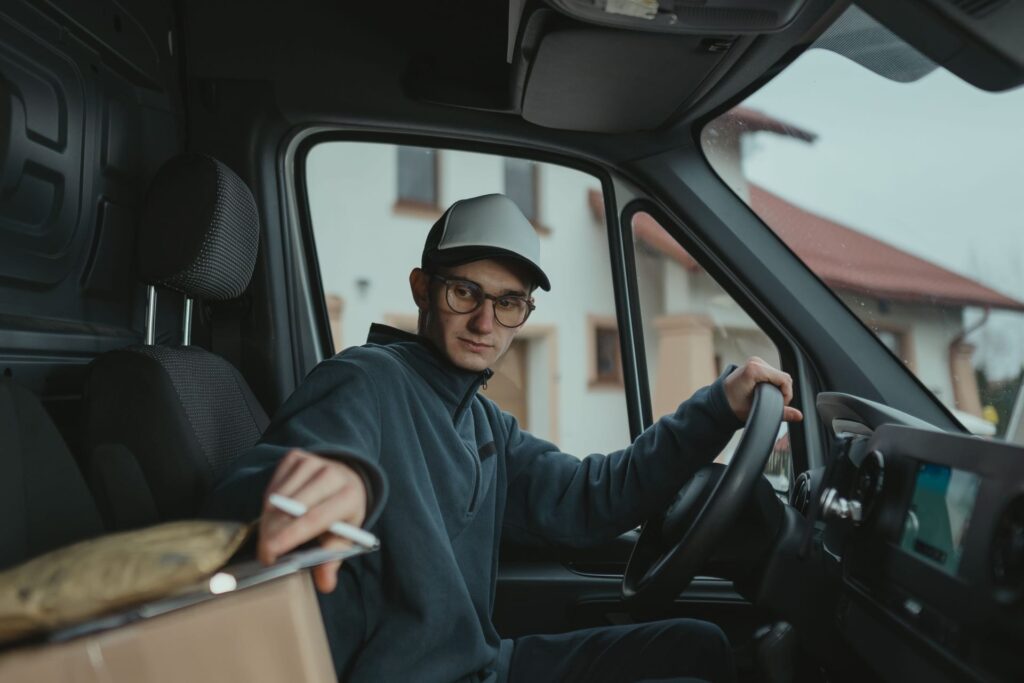 Young delivery driver inside a van preparing to deliver a package, showcasing logistics work.
