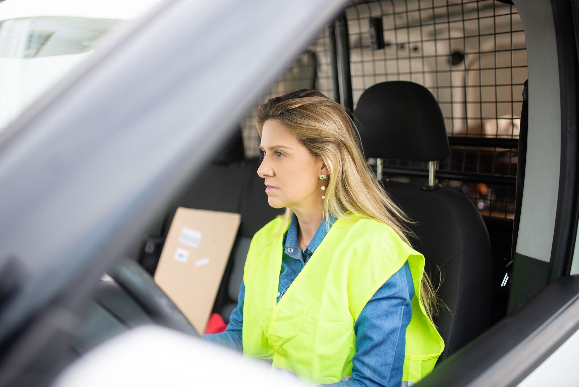 Driver at the wheel of a van with the load-area security cage visible behind the cab