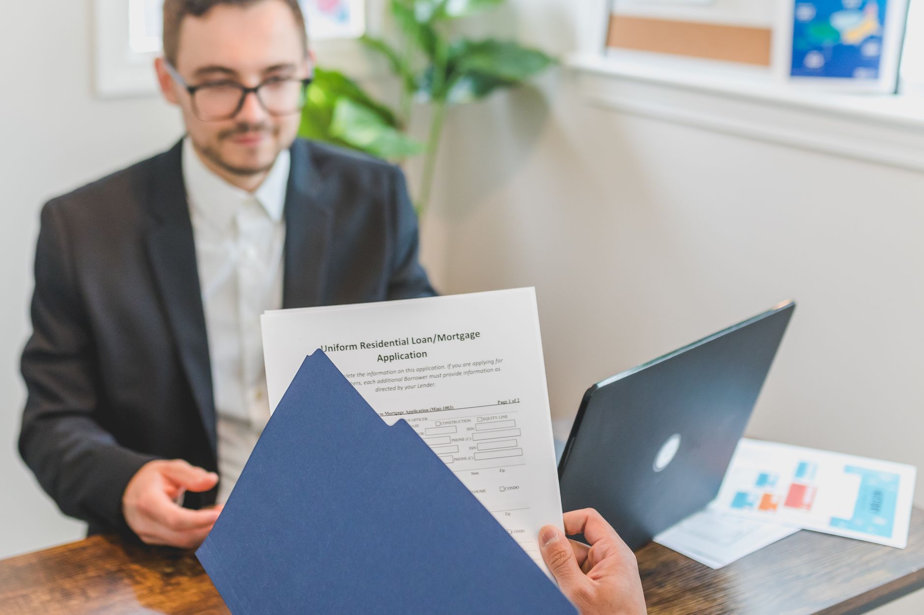 Person reviewing a folder of paperwork at a desk before completing an application