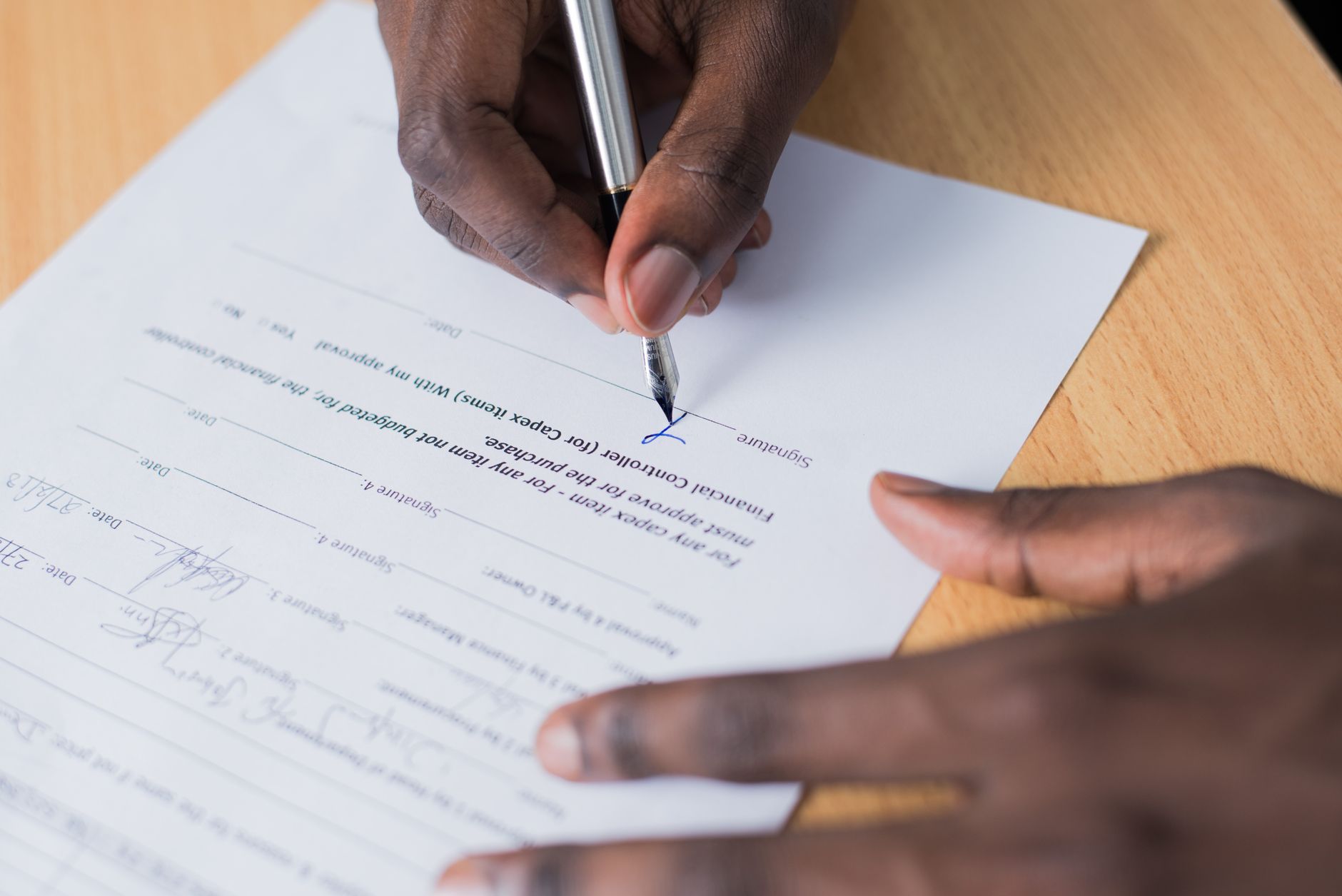 Hand signing an agreement document with a pen at a desk