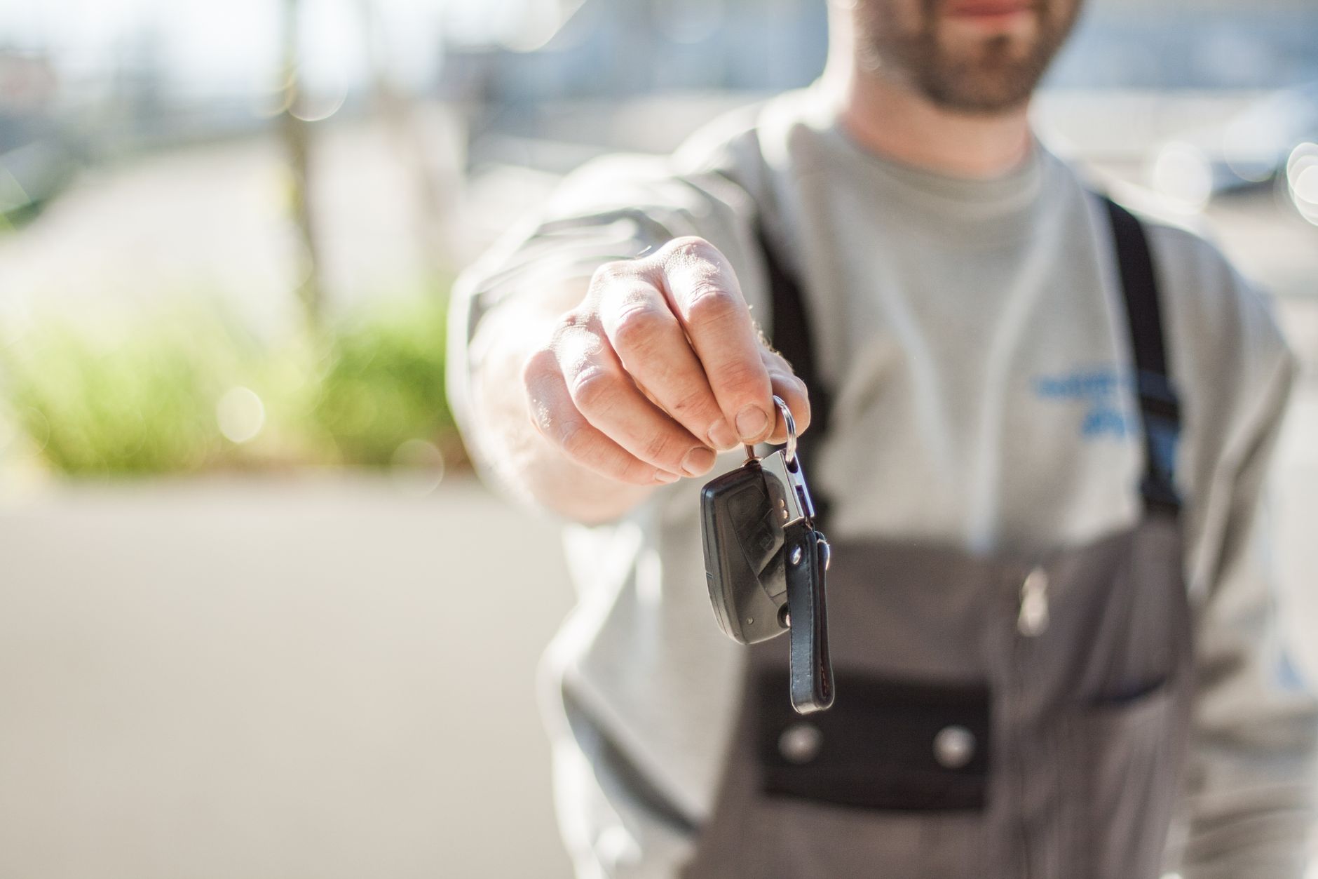 A hand offering a set of vehicle keys across a desk