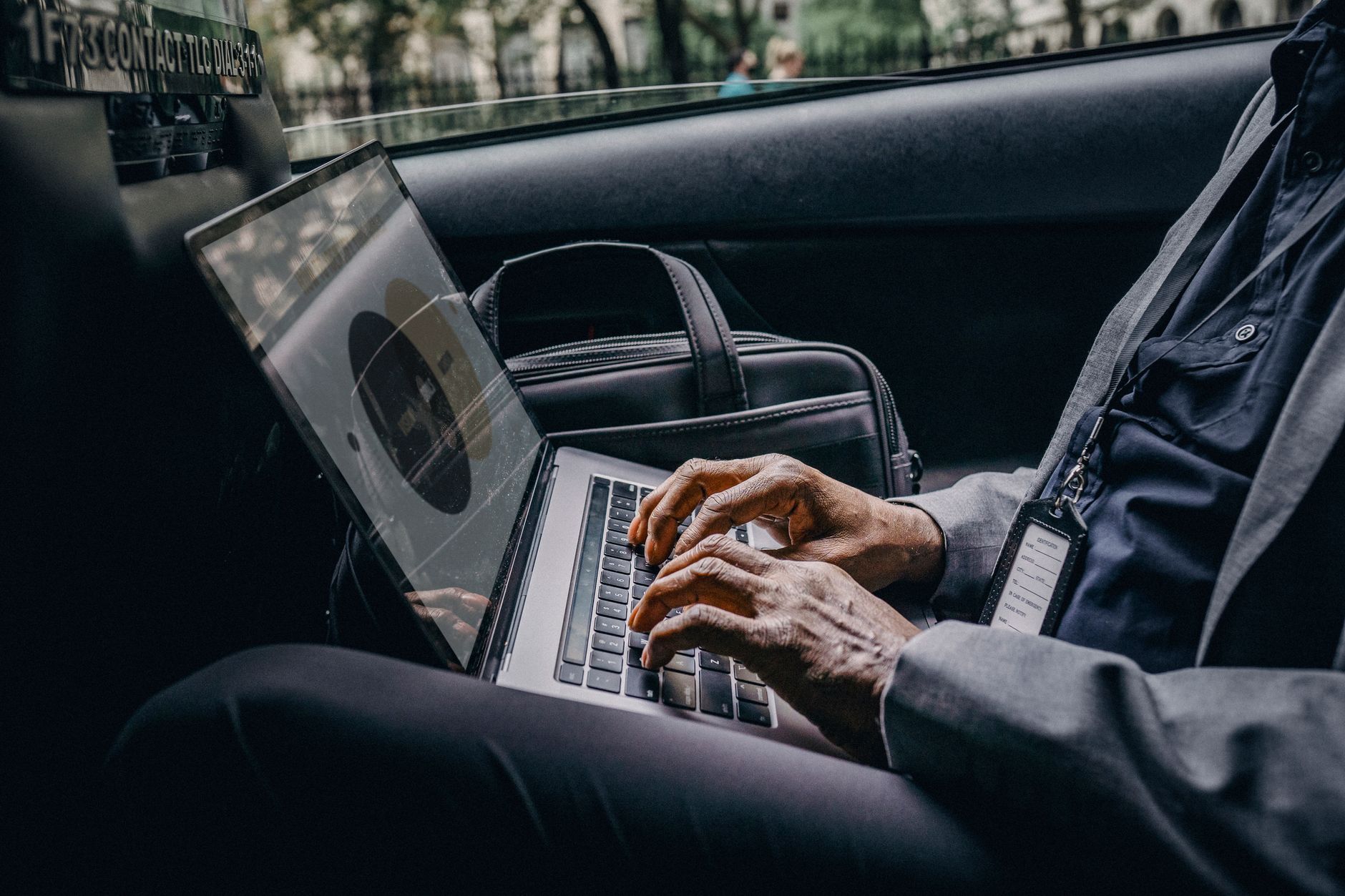Someone using a laptop to look up a vehicle valuation while sitting in a car