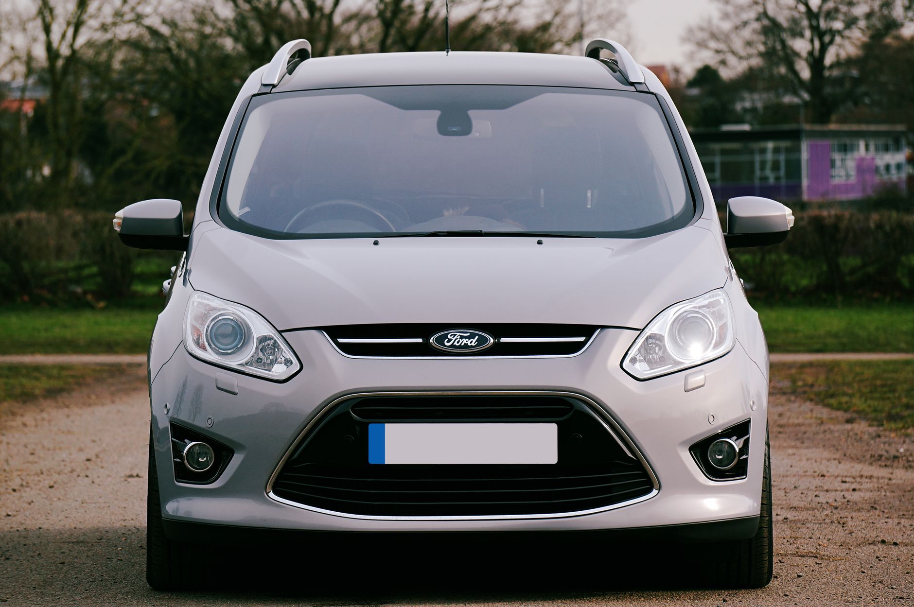 A man standing beside the open door of a white van, arms folded