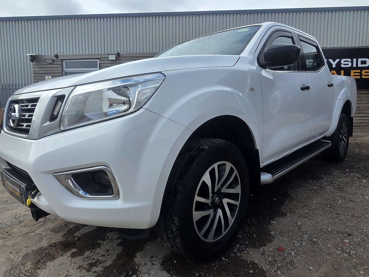 A double-cab pickup on a dealer forecourt, front three-quarter view