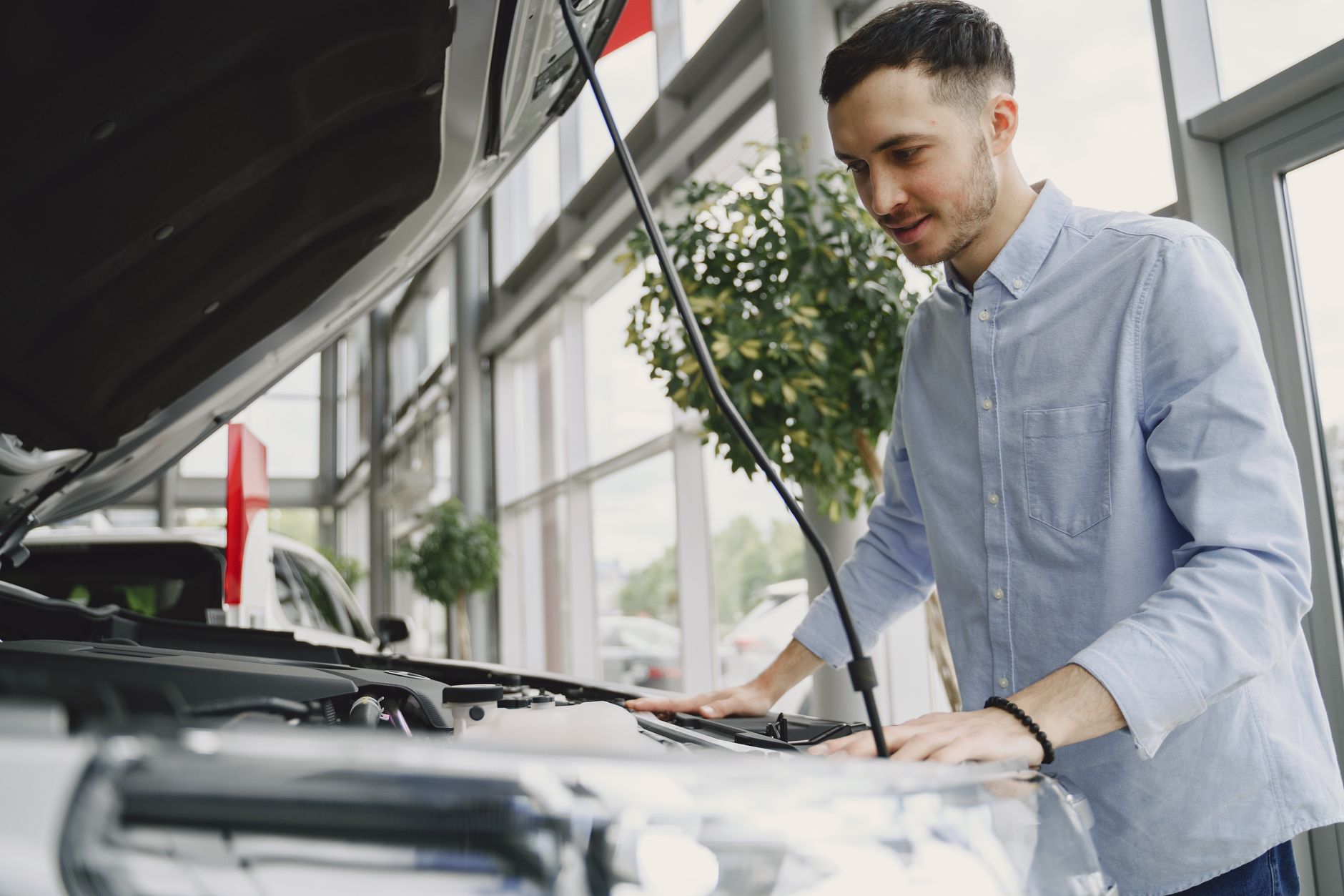 Buyer looking into the open engine bay of a vehicle at a dealership before purchase