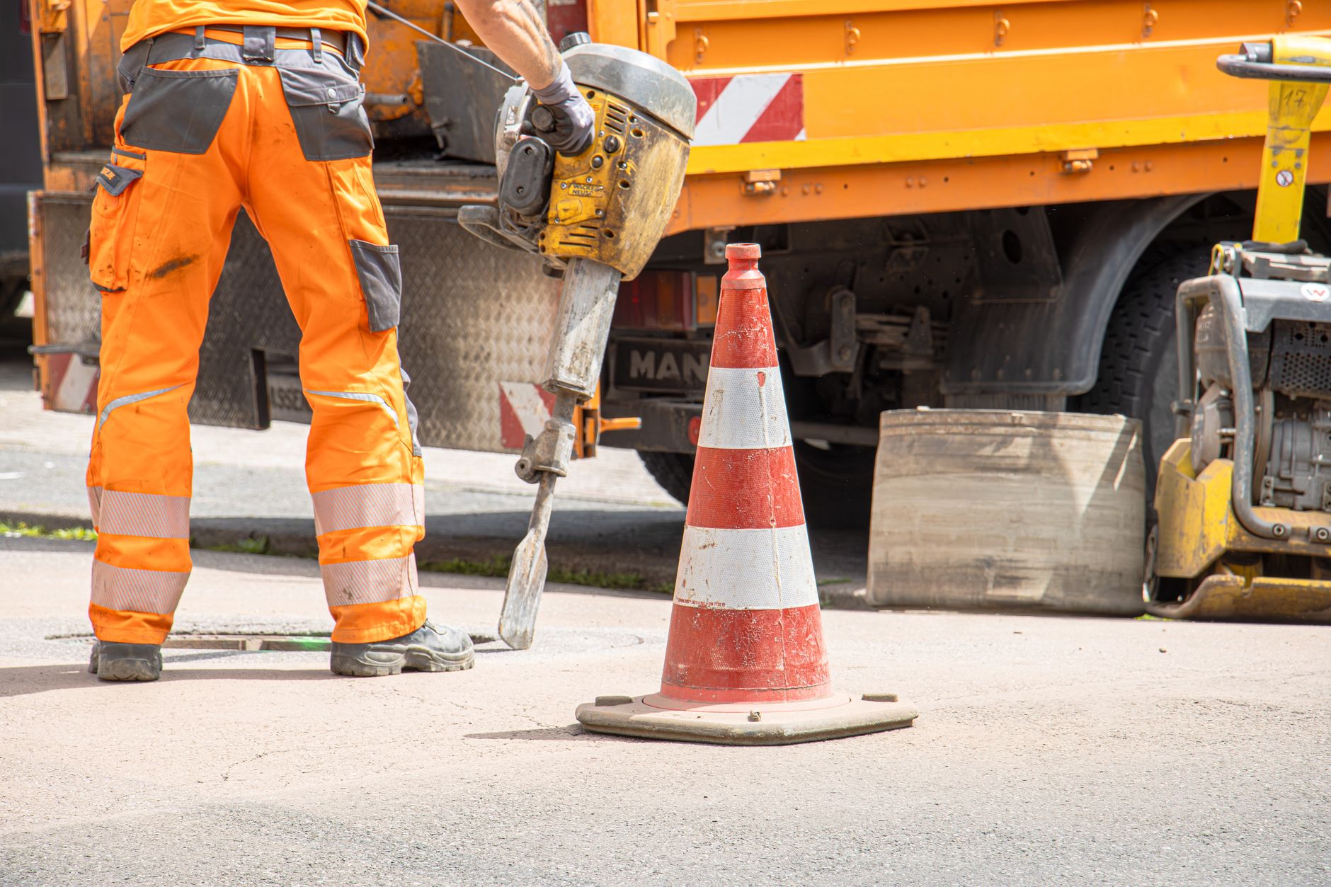 Road worker using a jackhammer beside a works van on a street repair job