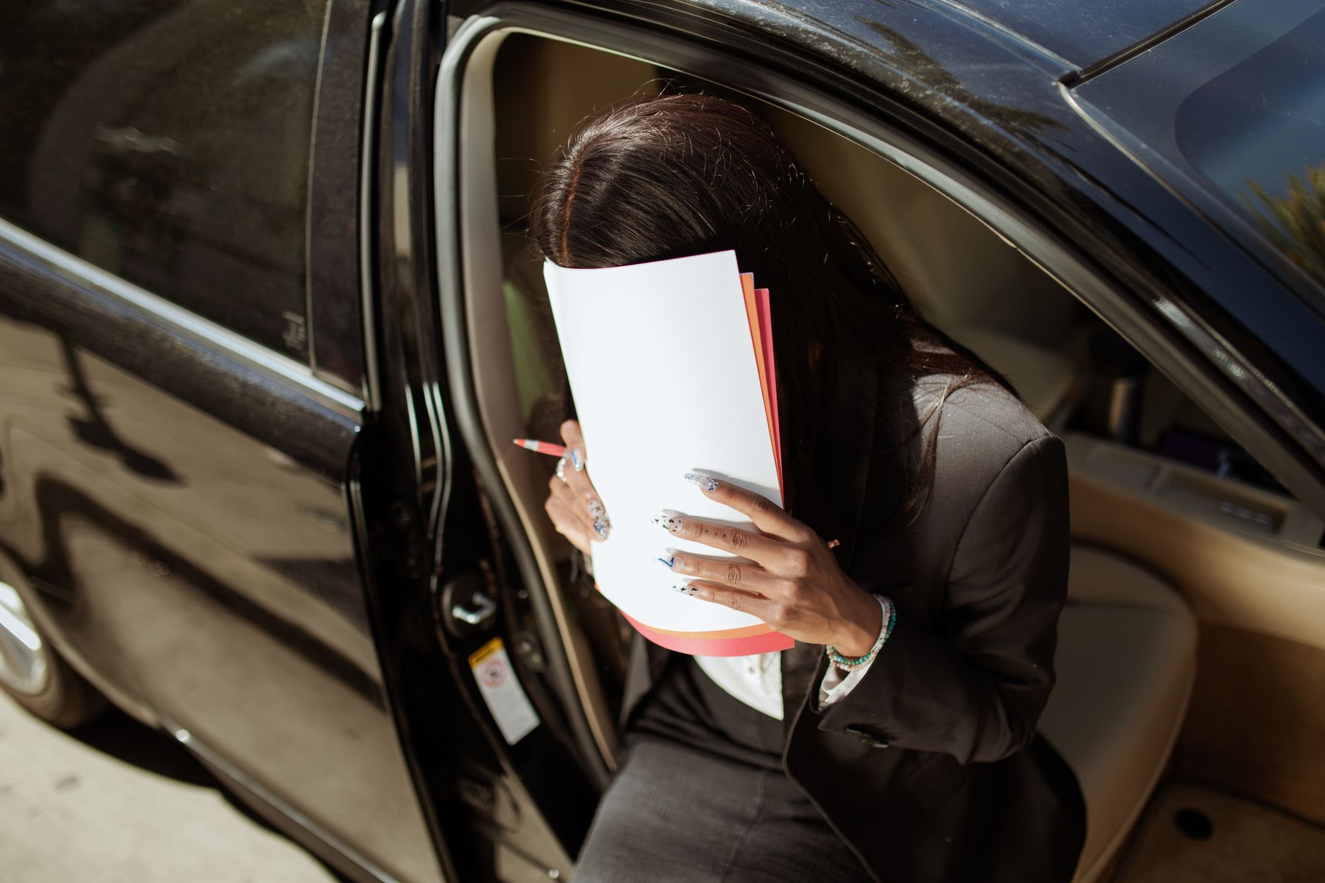 Buyer sitting in a vehicle reading through a folder of paperwork before signing