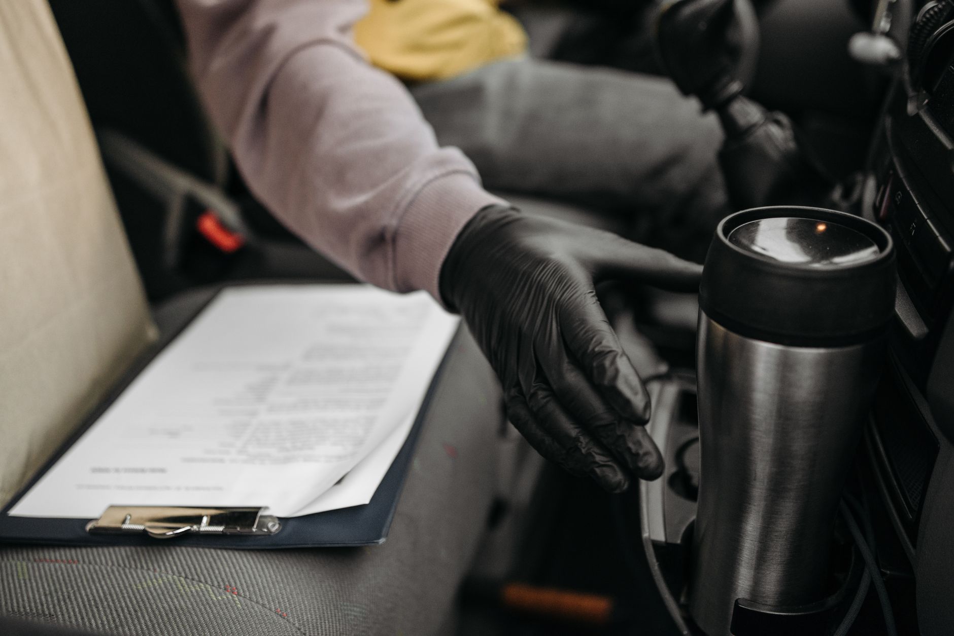 Gloved hand reaching across a clipboard holding a printed vehicle checklist