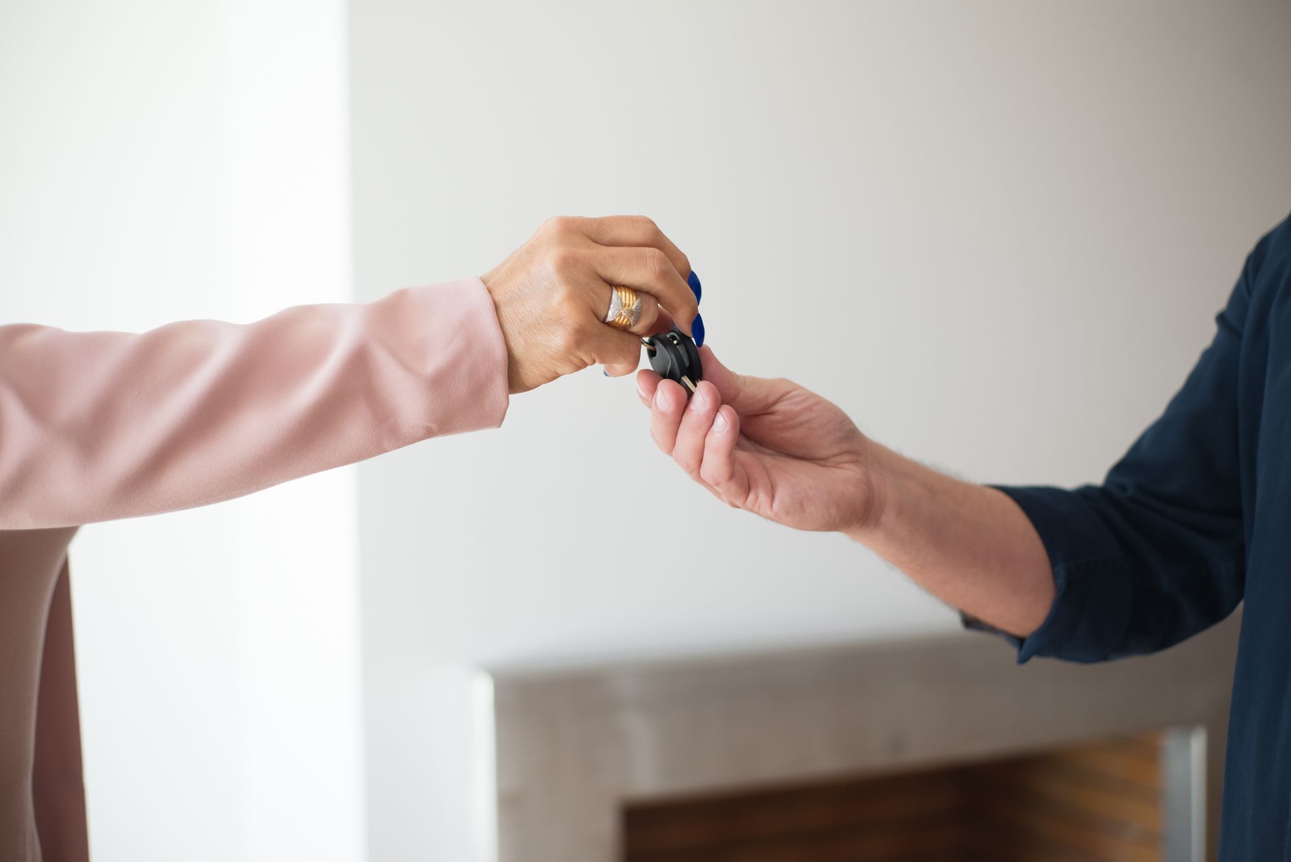 Close-up of vehicle keys being handed from one person to another at a handover