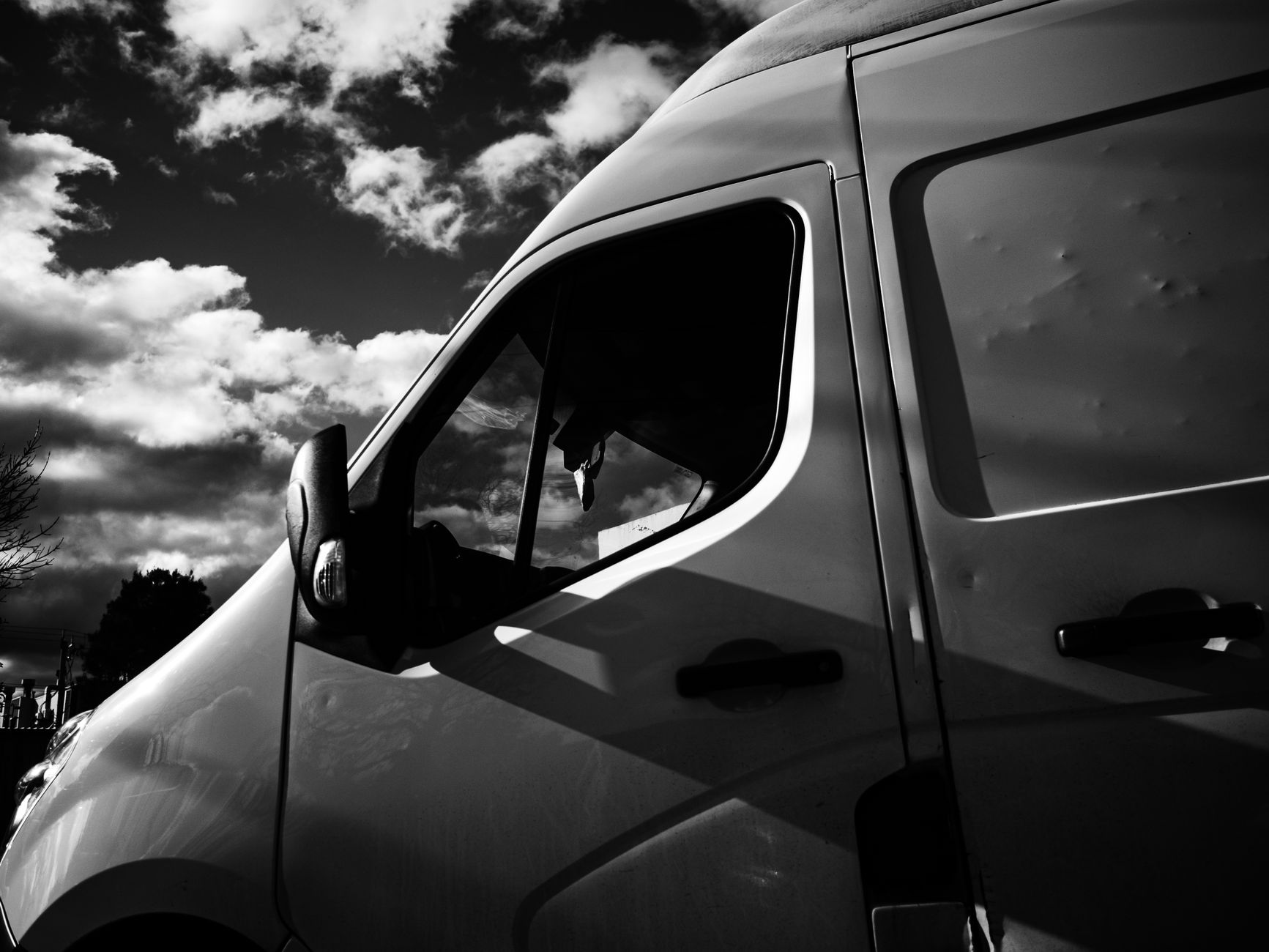 Close view of a van's side panel, mirror and roofline in black and white