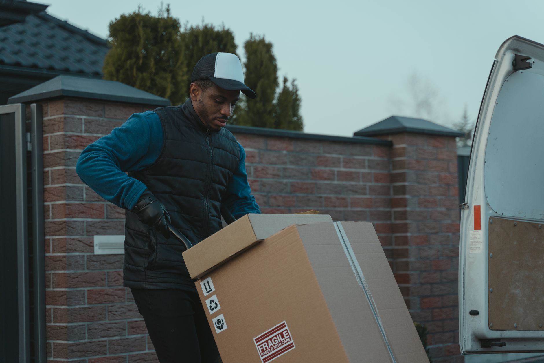 Worker carrying a box marked Fragile Handle With Care beside an open van door