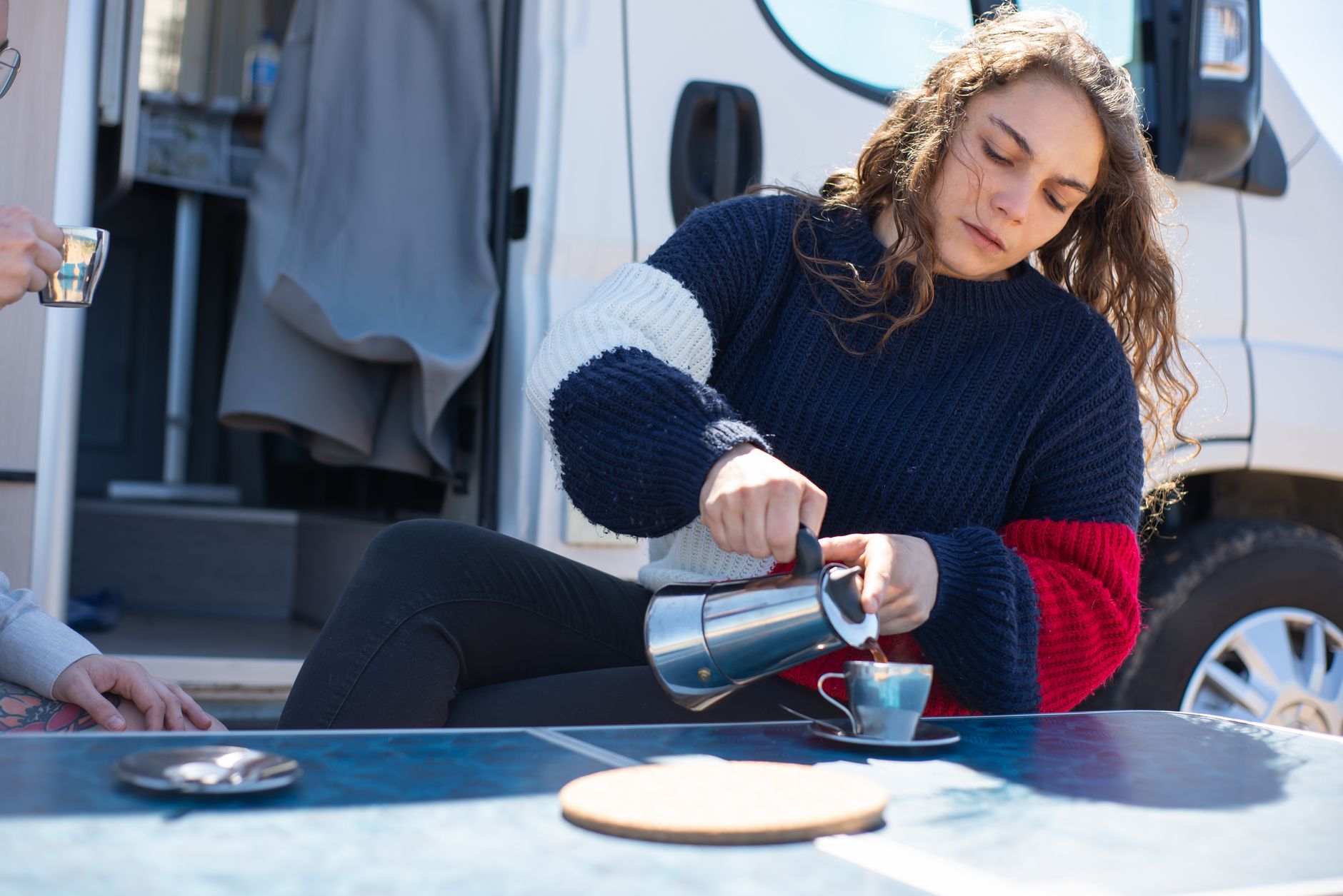 Coffee pot poured beside a fold-out table at the back of a converted van