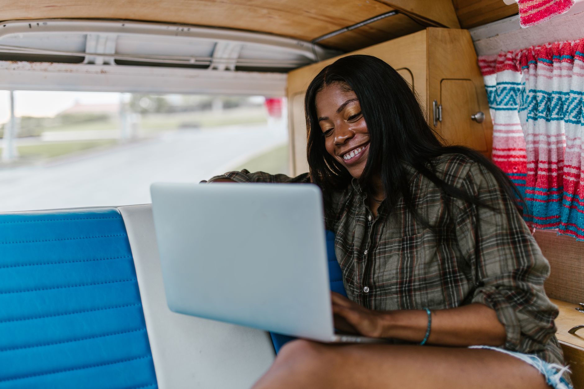 Person working on a laptop in the open side door of a parked van