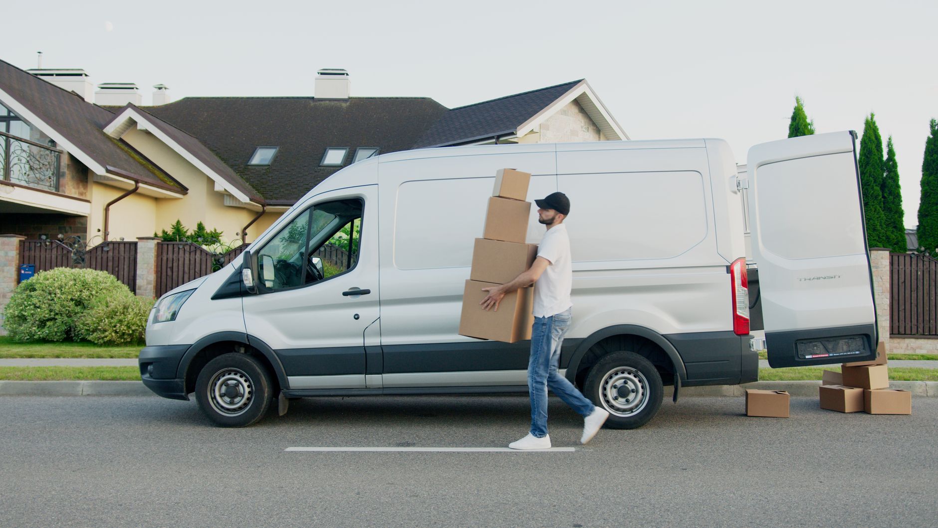 Delivery driver unloading boxes beside a Ford Transit with the badge visible