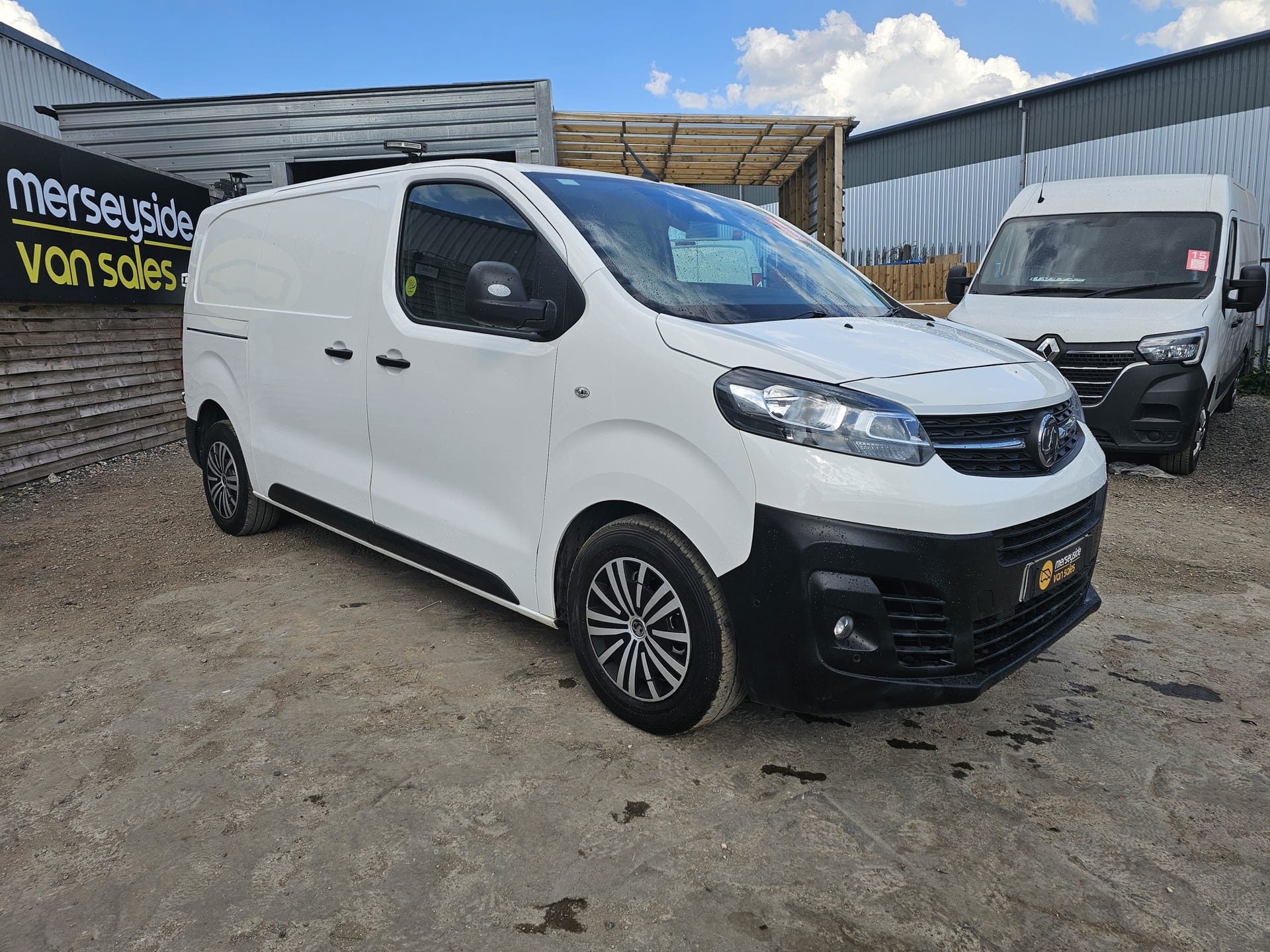 A white Vauxhall Vivaro panel van on the forecourt beneath the Merseyside Van Sales sign