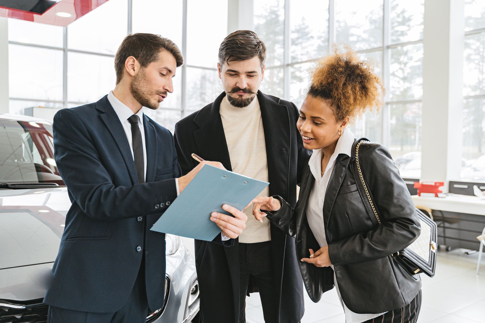 A salesperson going through a clipboard of paperwork with two customers