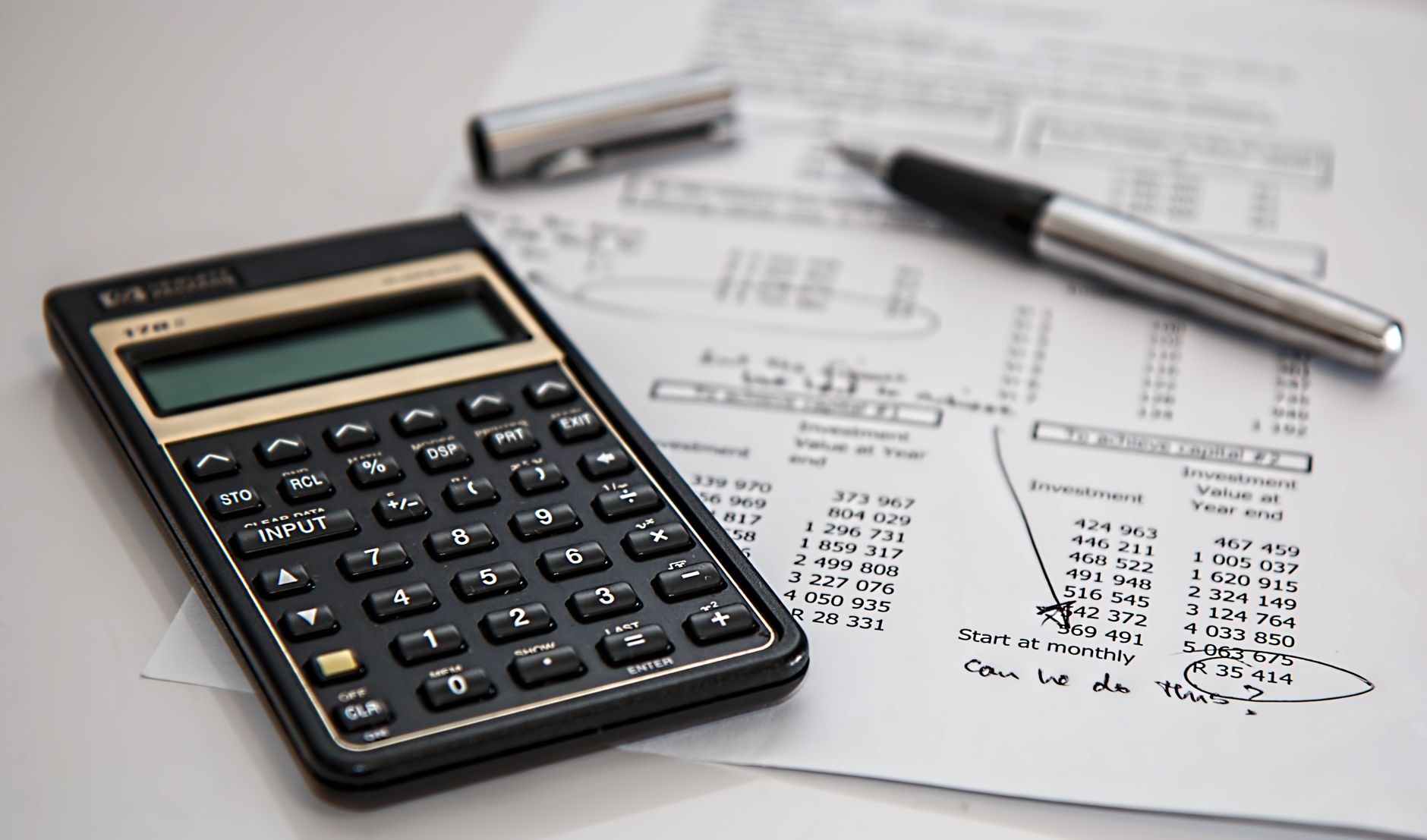 A calculator resting beside a page of handwritten workings