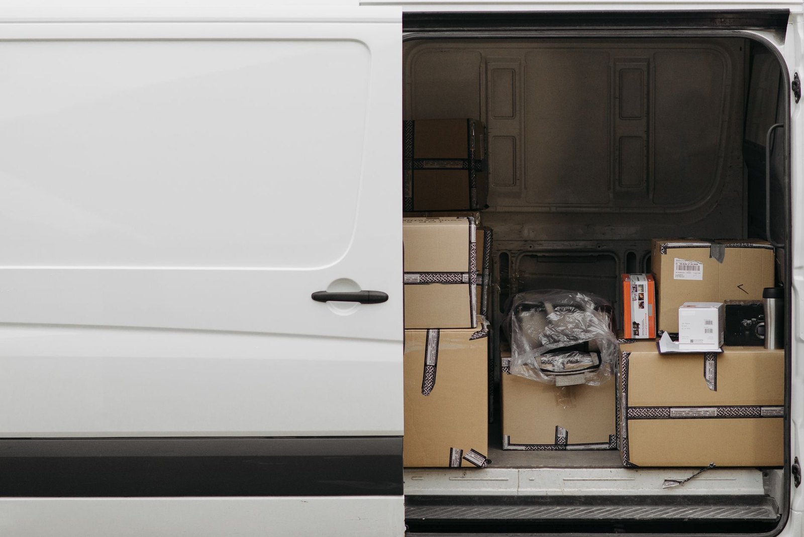 Cardboard parcels stacked inside a white van seen through the open side door