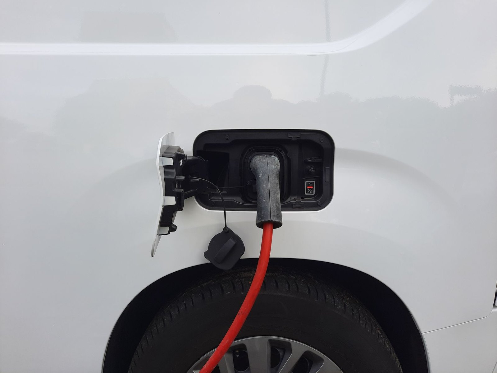 A charging cable plugged into the charge port of a white vehicle