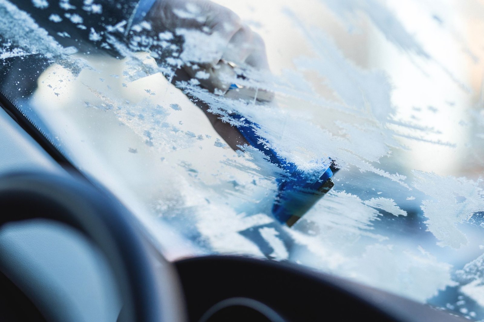 Frost on a windscreen being cleared with a scraper from outside