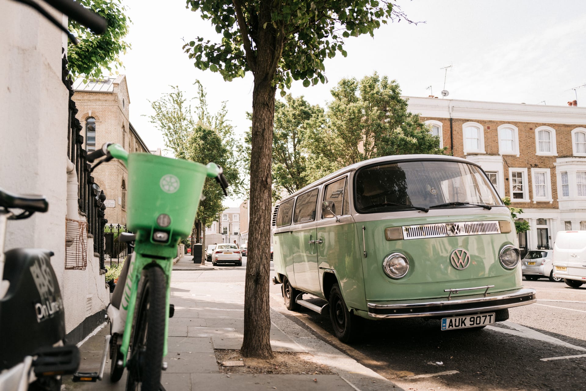 A vintage green Volkswagen van parked on a sunny London street, capturing urban charm.