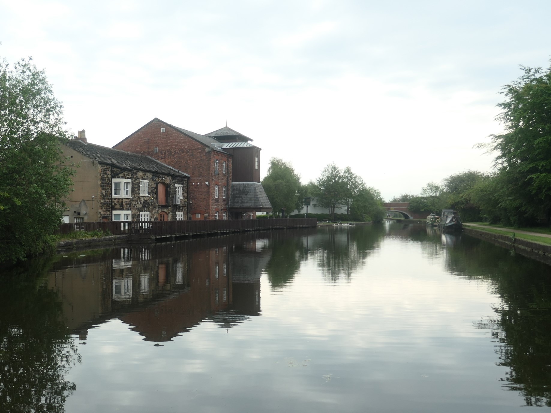 Old brick and stone wharf buildings reflected in the canal at Leigh
