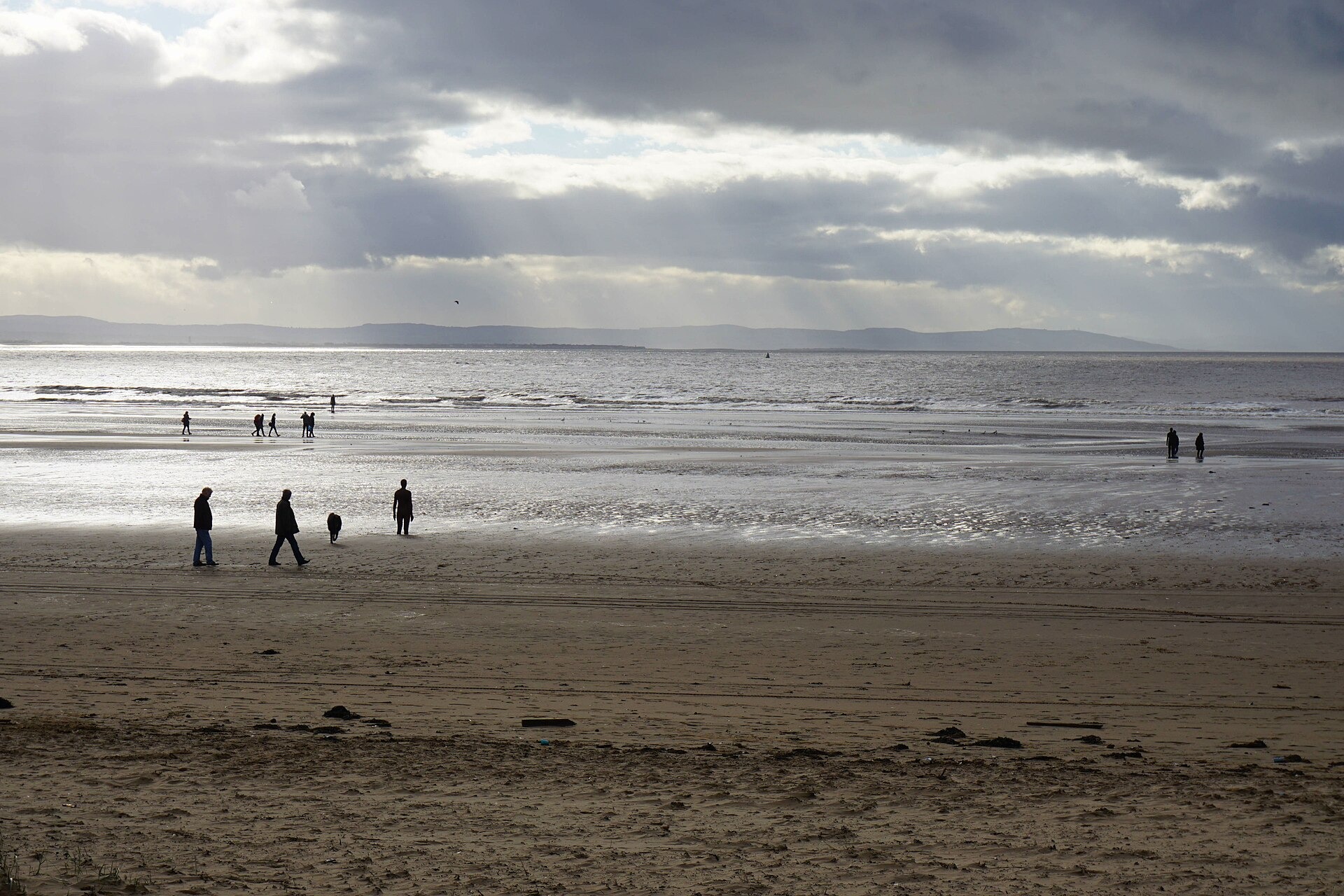 Walkers on the wide sands at Crosby with the tide a long way out