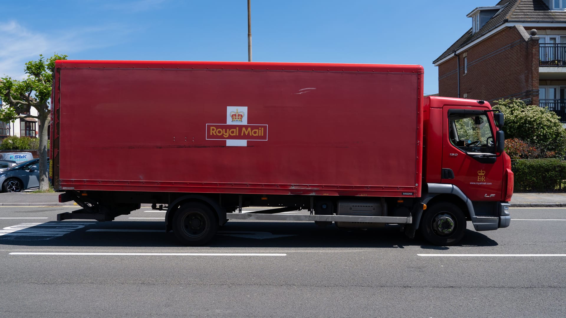 A bright red Royal Mail truck parked on a sunny street in Portsmouth, UK.